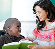 a teacher reading to a young smiling student