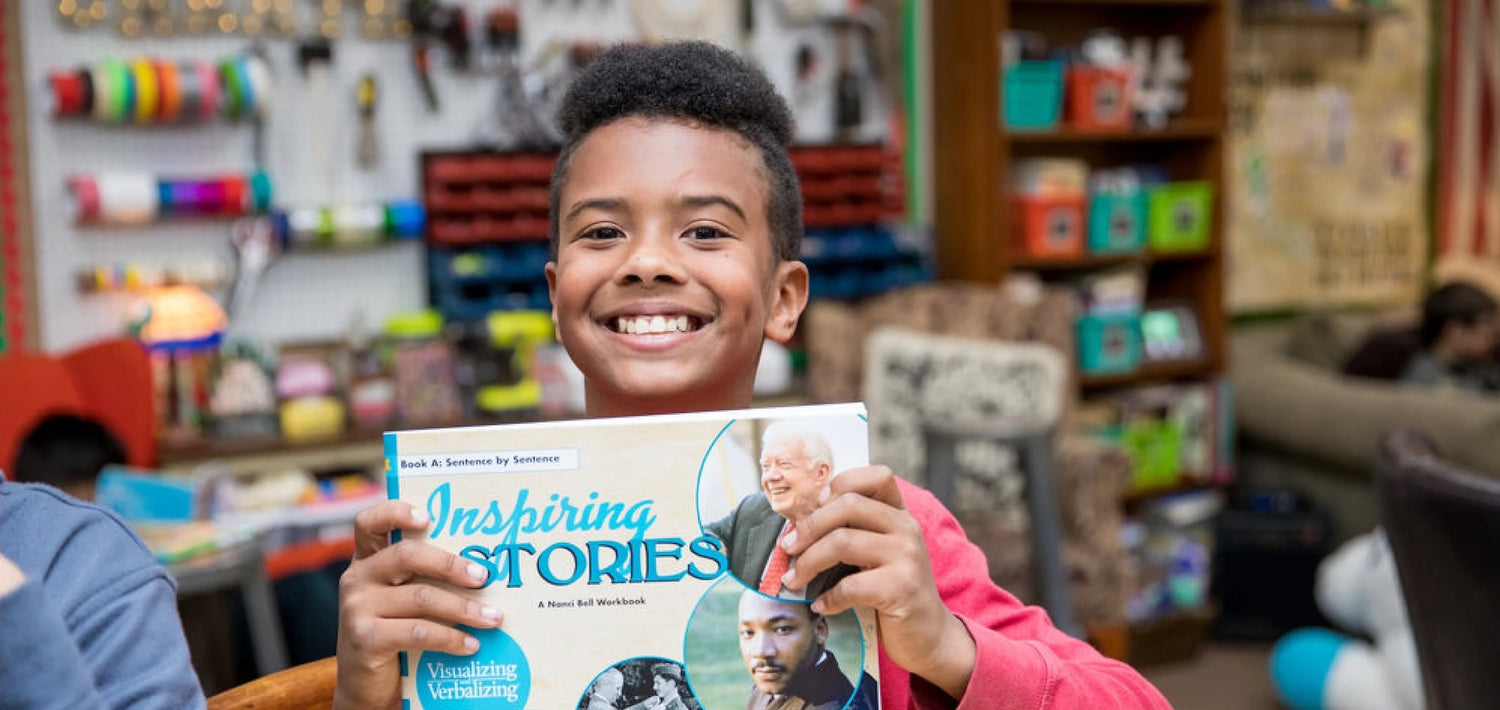 Smiling child holding up an Inspiring Stories Visualizing and Verbalizing book